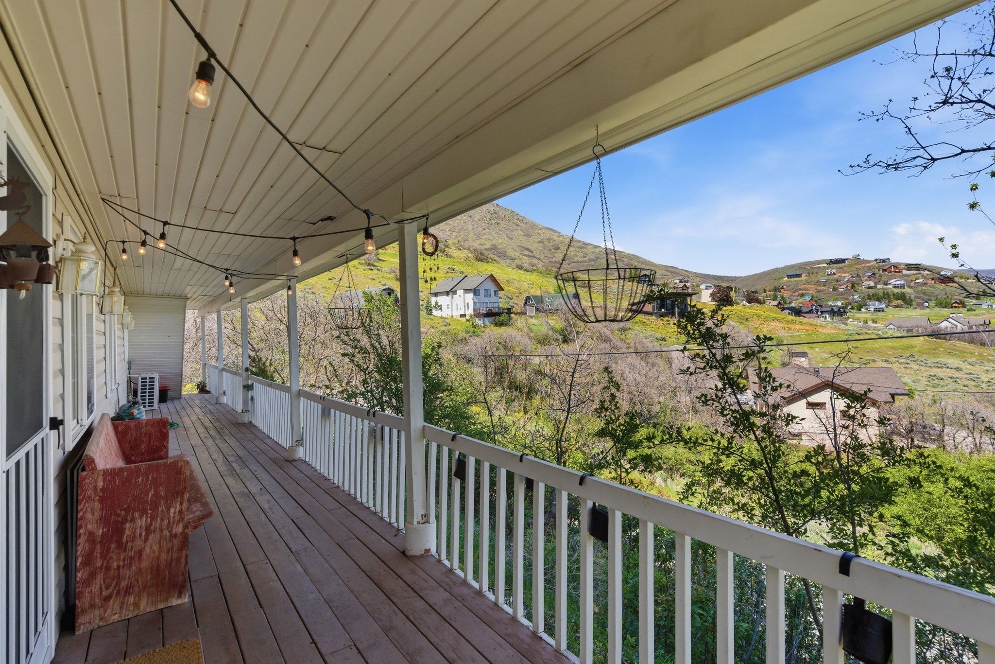 Expansive covered porch featuring wood-finish flooring, white railing, and string lighting