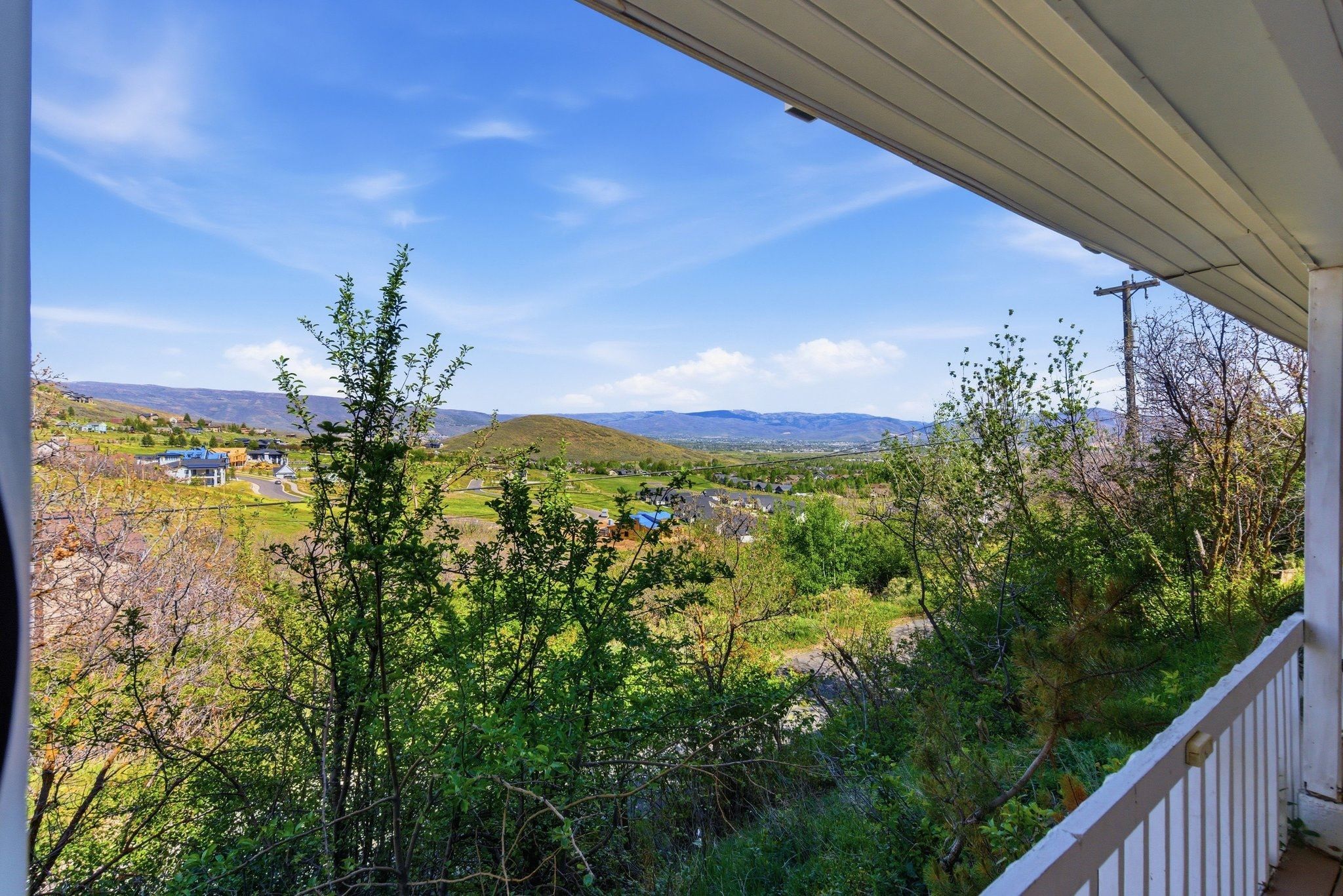 Expansive mountain and valley scenery observed from a covered porch featuring a white railing