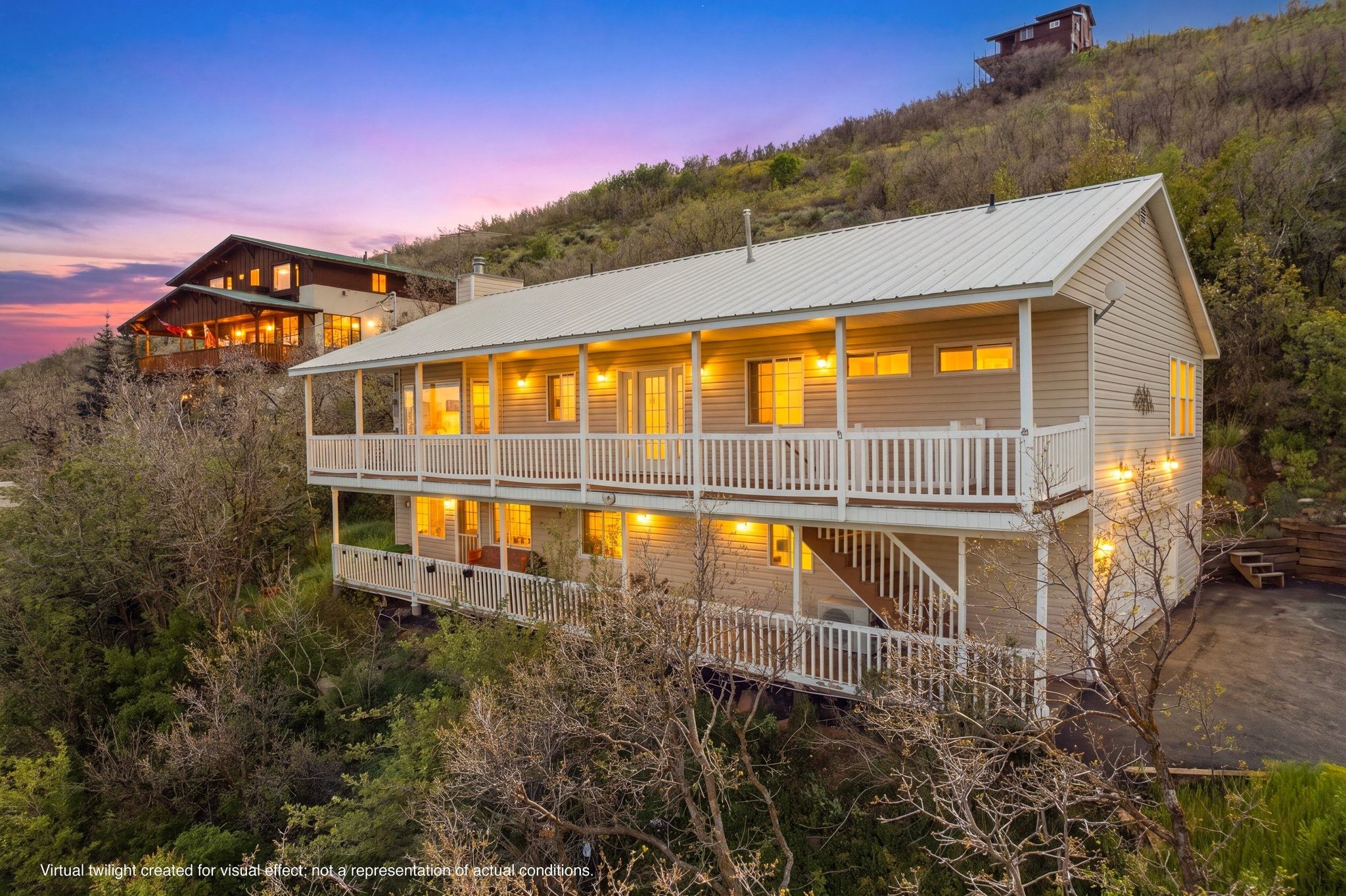 Hillside residence featuring multi-level balconies with white railings and beige siding