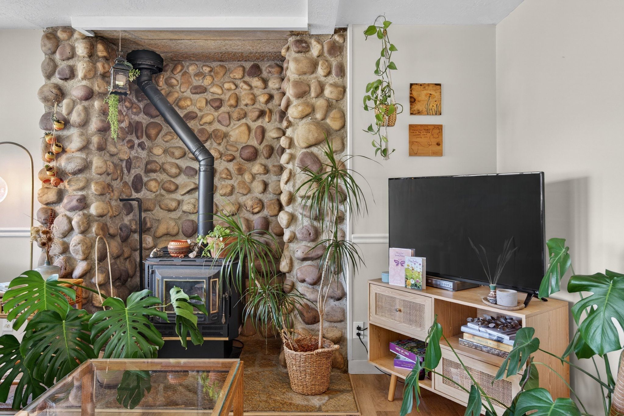 River rock accent wall featuring a black wood-burning stove with a matching stovepipe