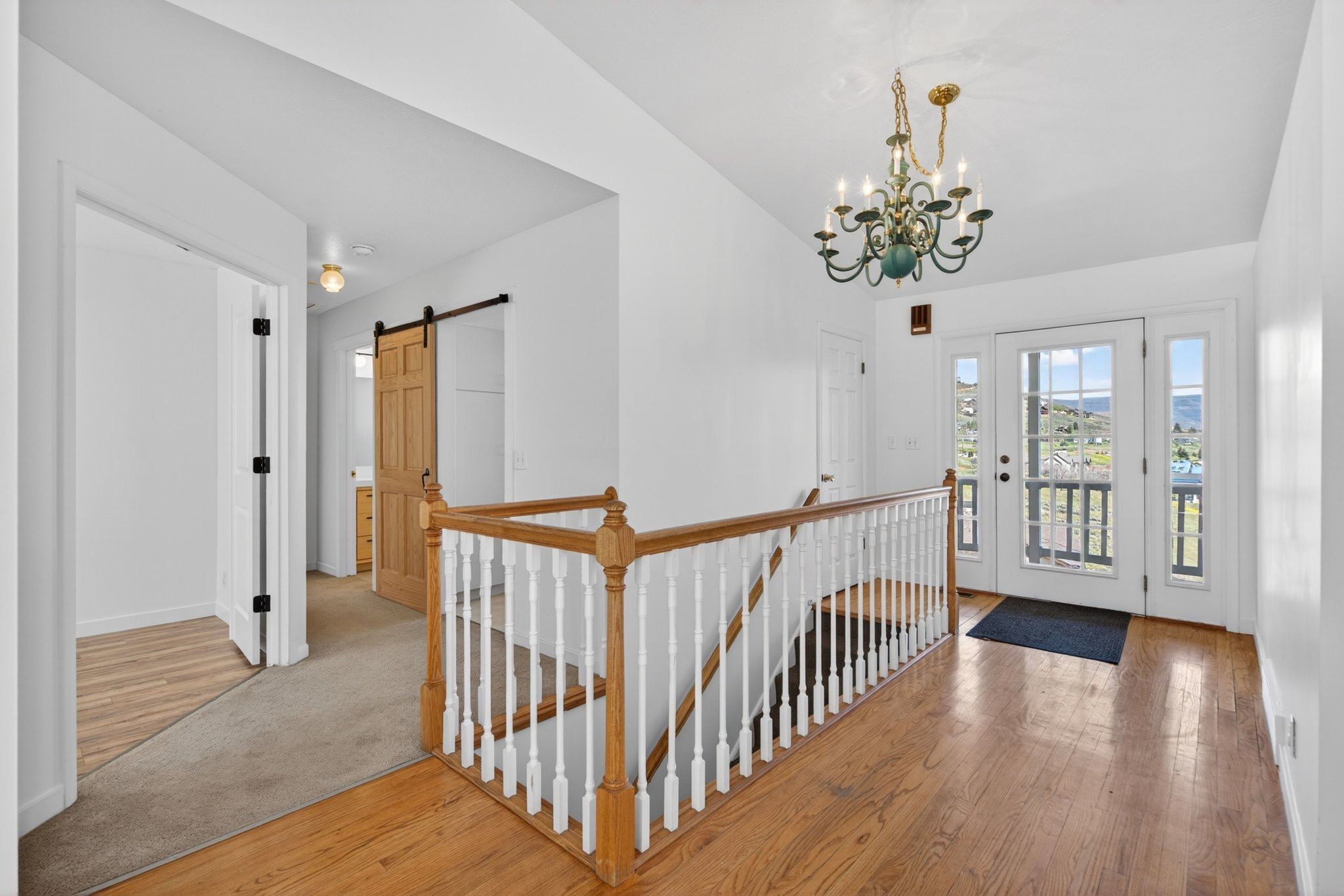 Hardwood flooring entry with a classic chandelier and white painted balusters
