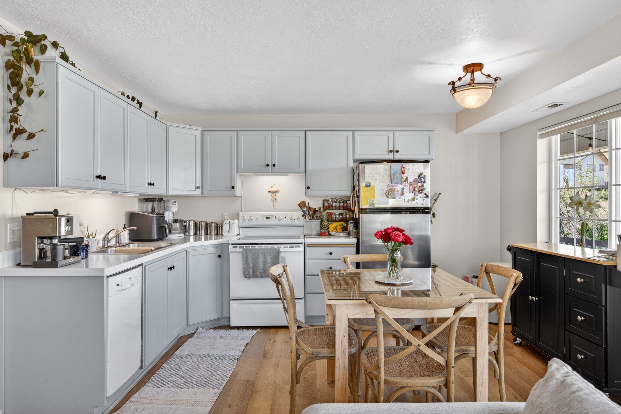 Kitchen featuring light blue cabinetry, white countertops, built-in dishwasher, and wood-finish flooring