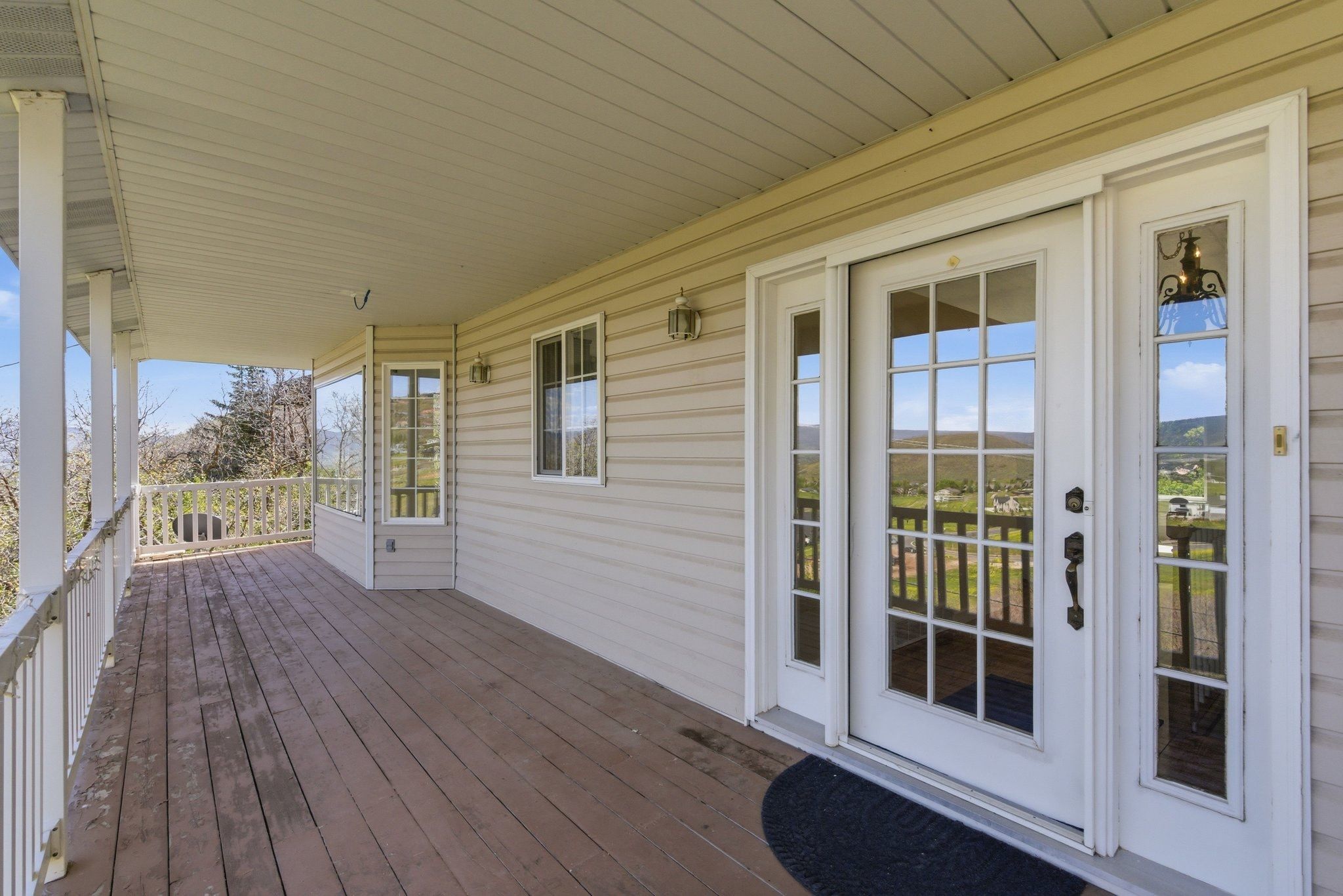 Expansive covered porch with wood-finish flooring, white railing, and multiple support columns