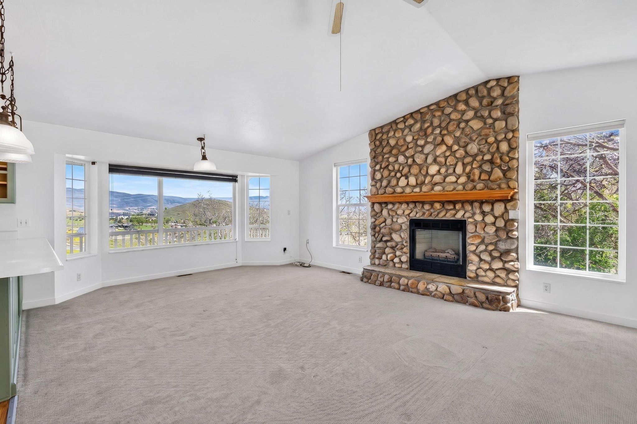 Spacious room featuring a prominent stone-clad fireplace with a wood mantel