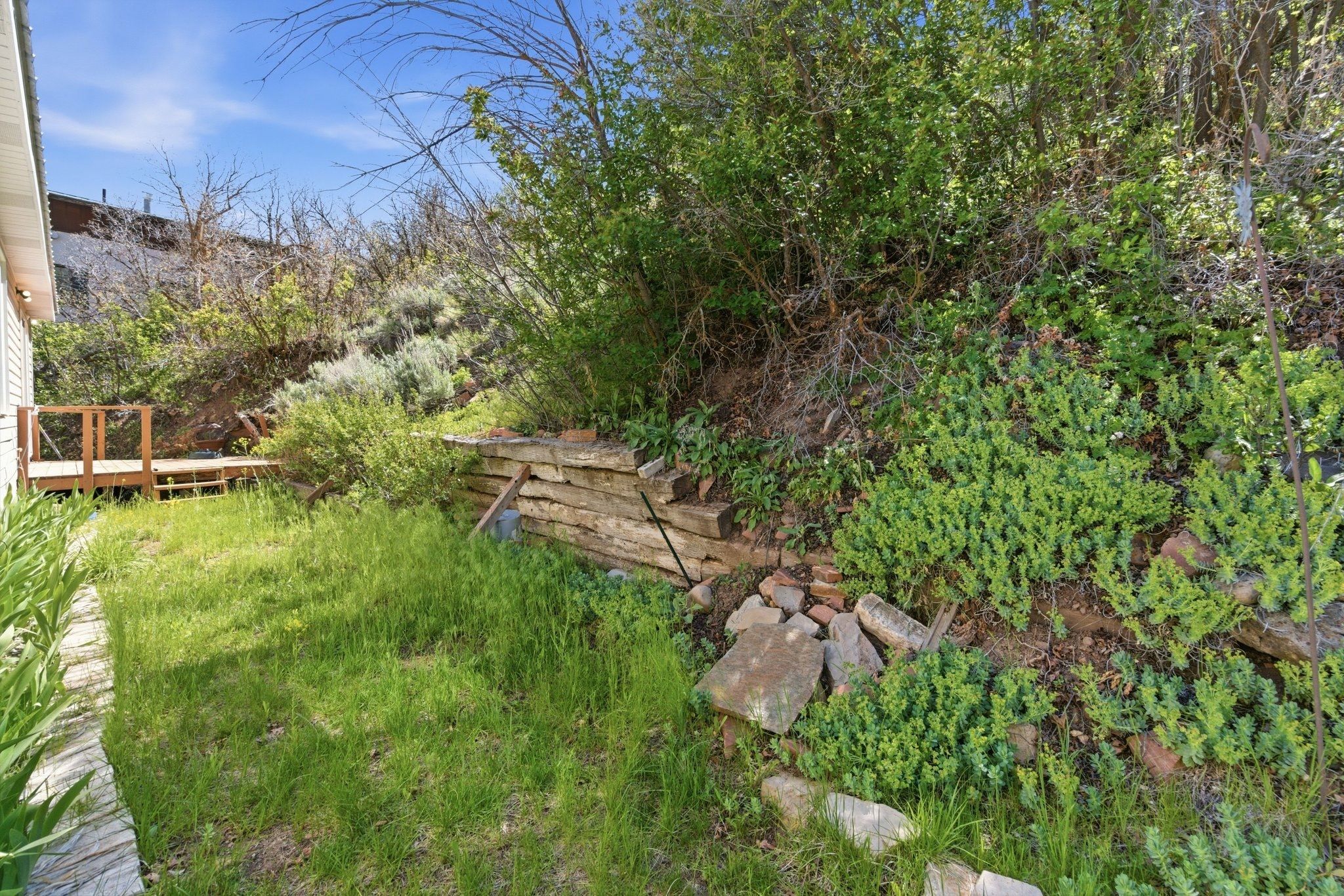 Tiered landscaping with a wooden retaining wall, a multi-level deck, and a grass area