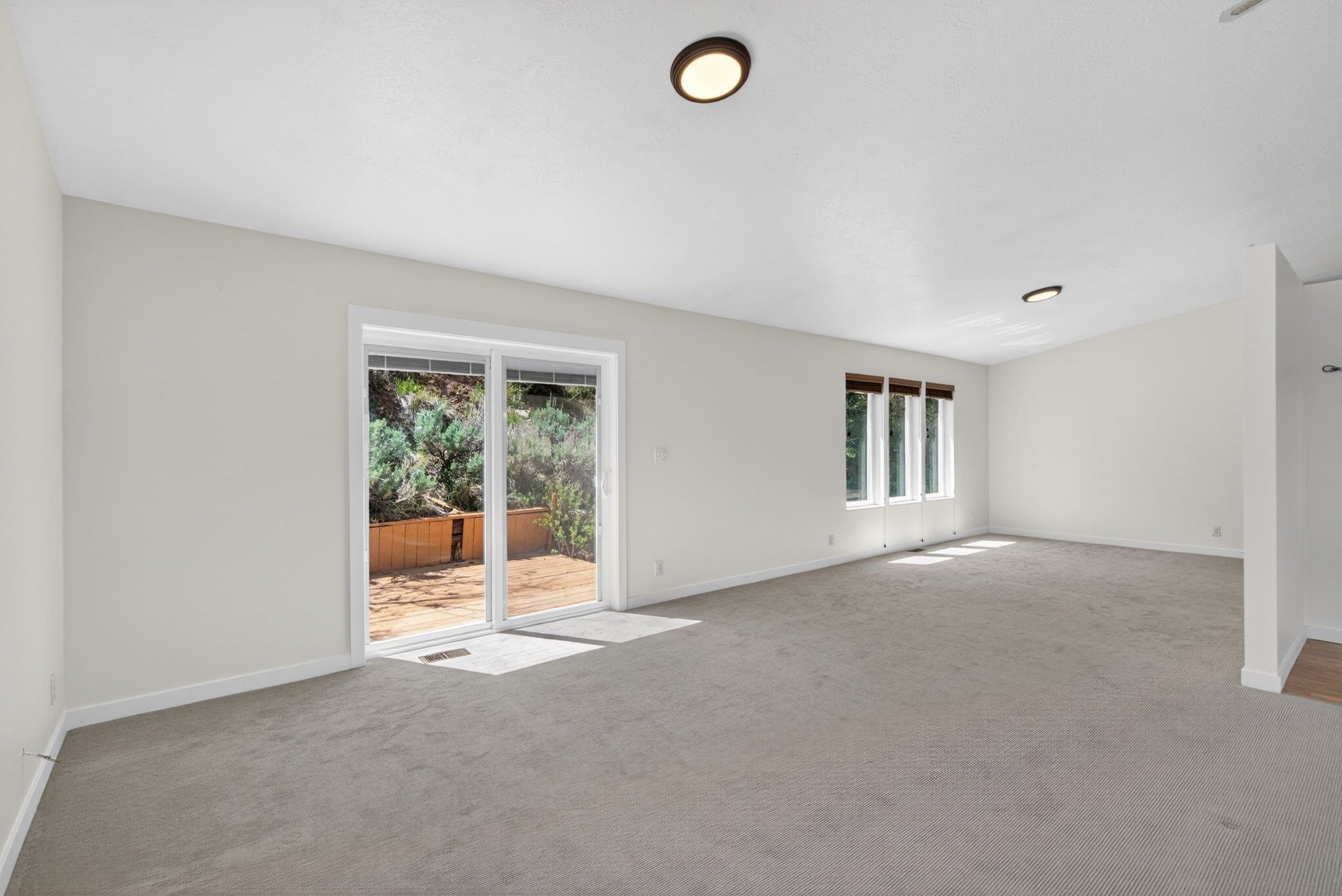 Expansive room featuring light gray carpet flooring and white painted walls