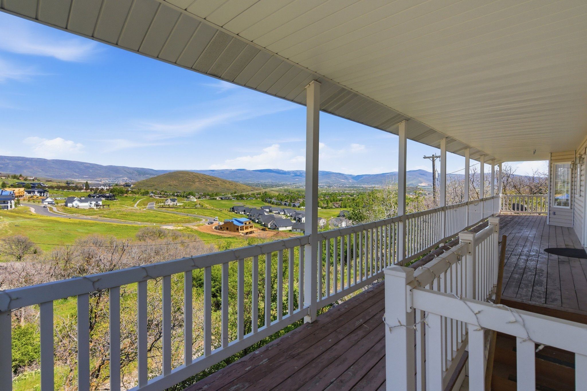 Expansive covered deck featuring wood-finish flooring and white railings