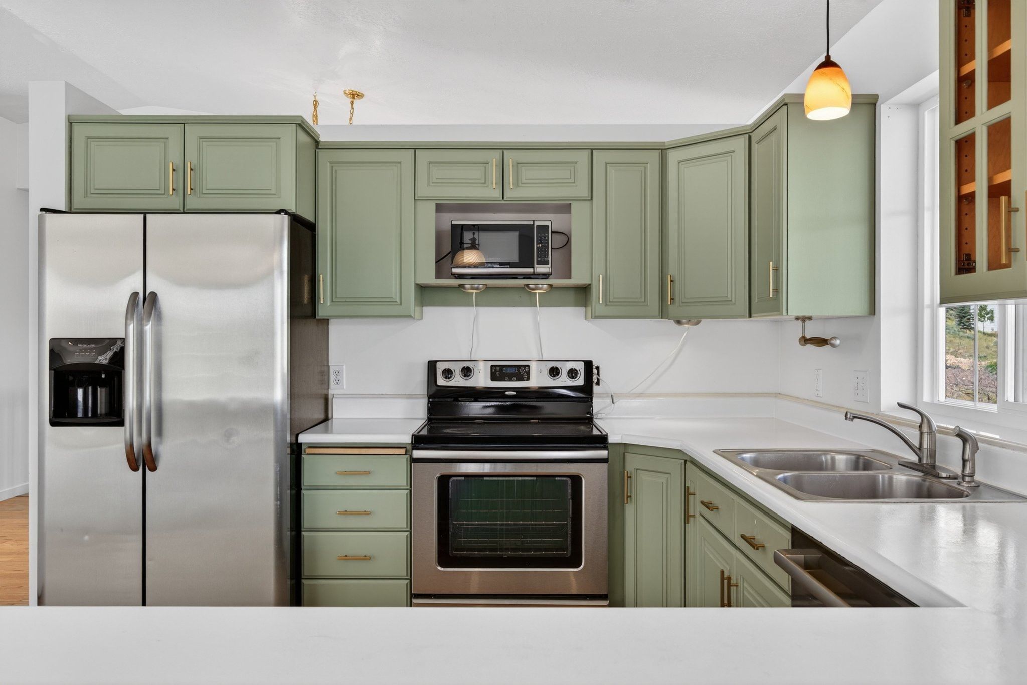 Kitchen featuring sage green cabinetry, stainless steel appliances, a double basin sink, and white countertops