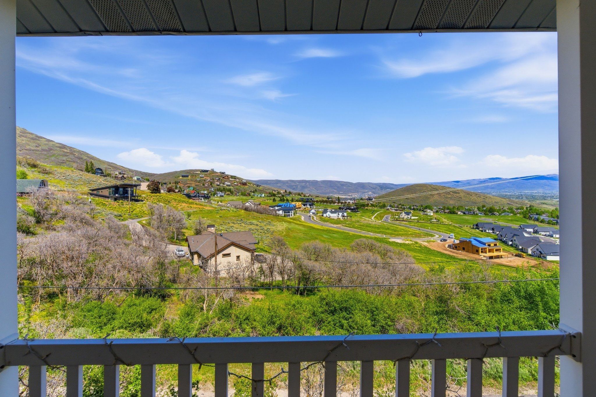Expansive hillside scenery featuring distant mountains and scattered residential properties