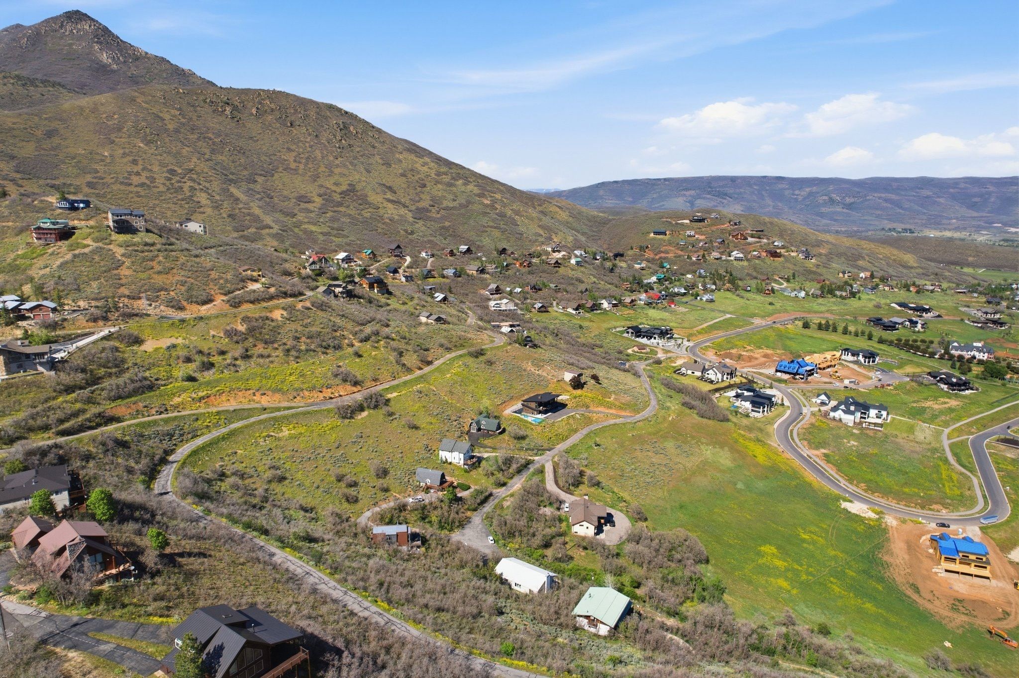 Rolling hills with scattered residential structures, featuring winding roads and varied topography