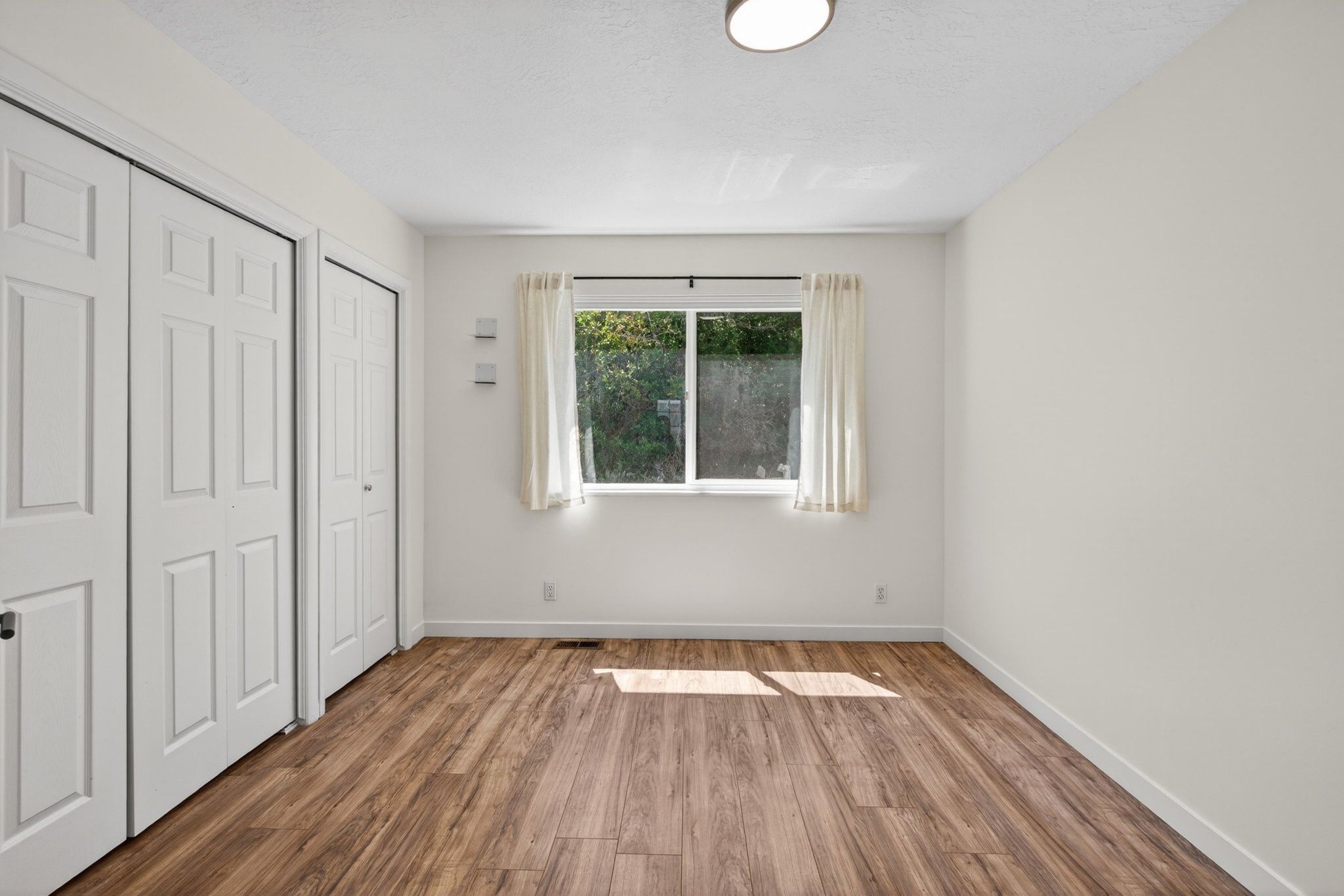 Room featuring wood-finish flooring, white walls, and a recessed ceiling light