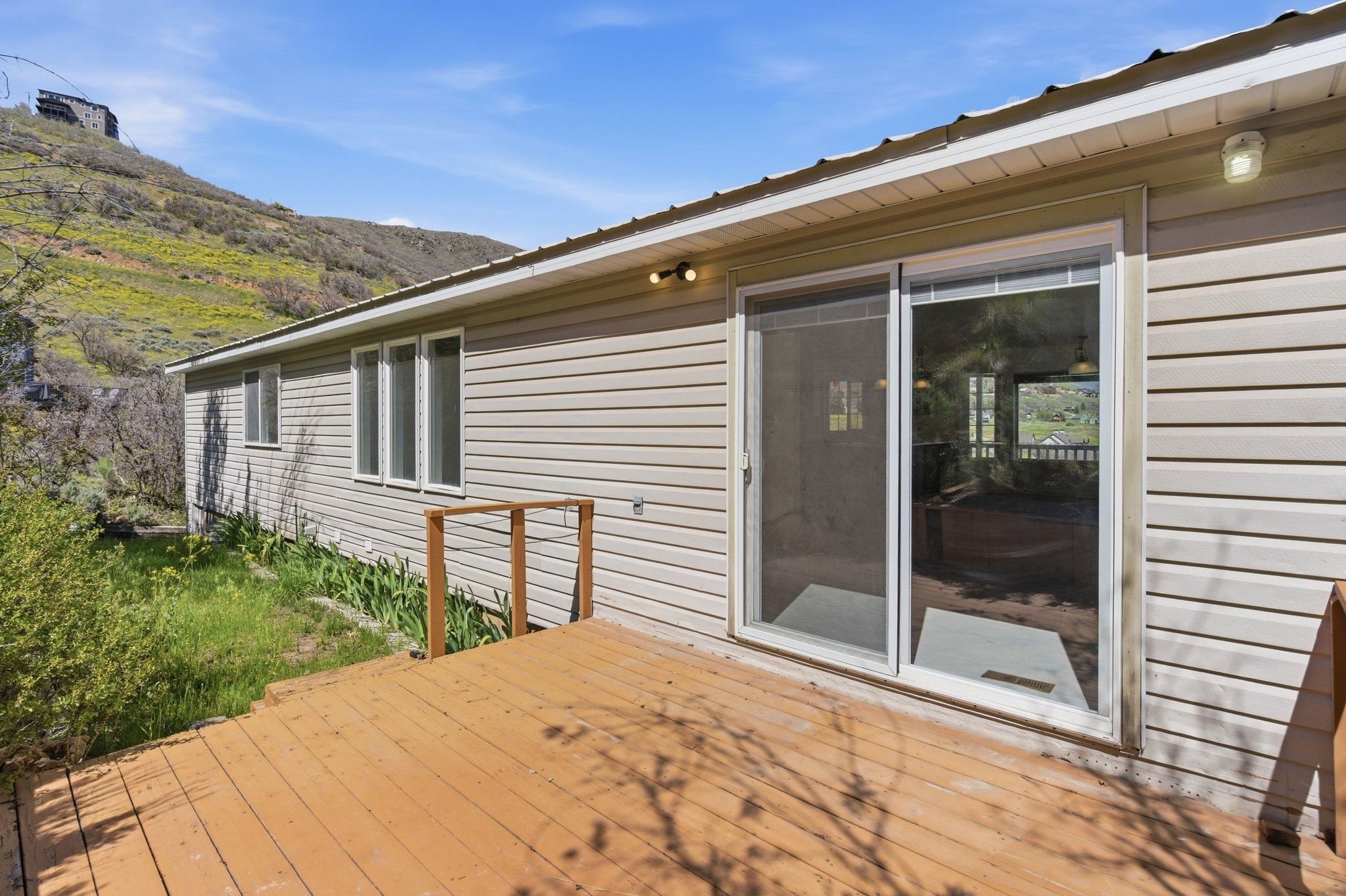 Outdoor wooden deck featuring a sliding glass door and side windows