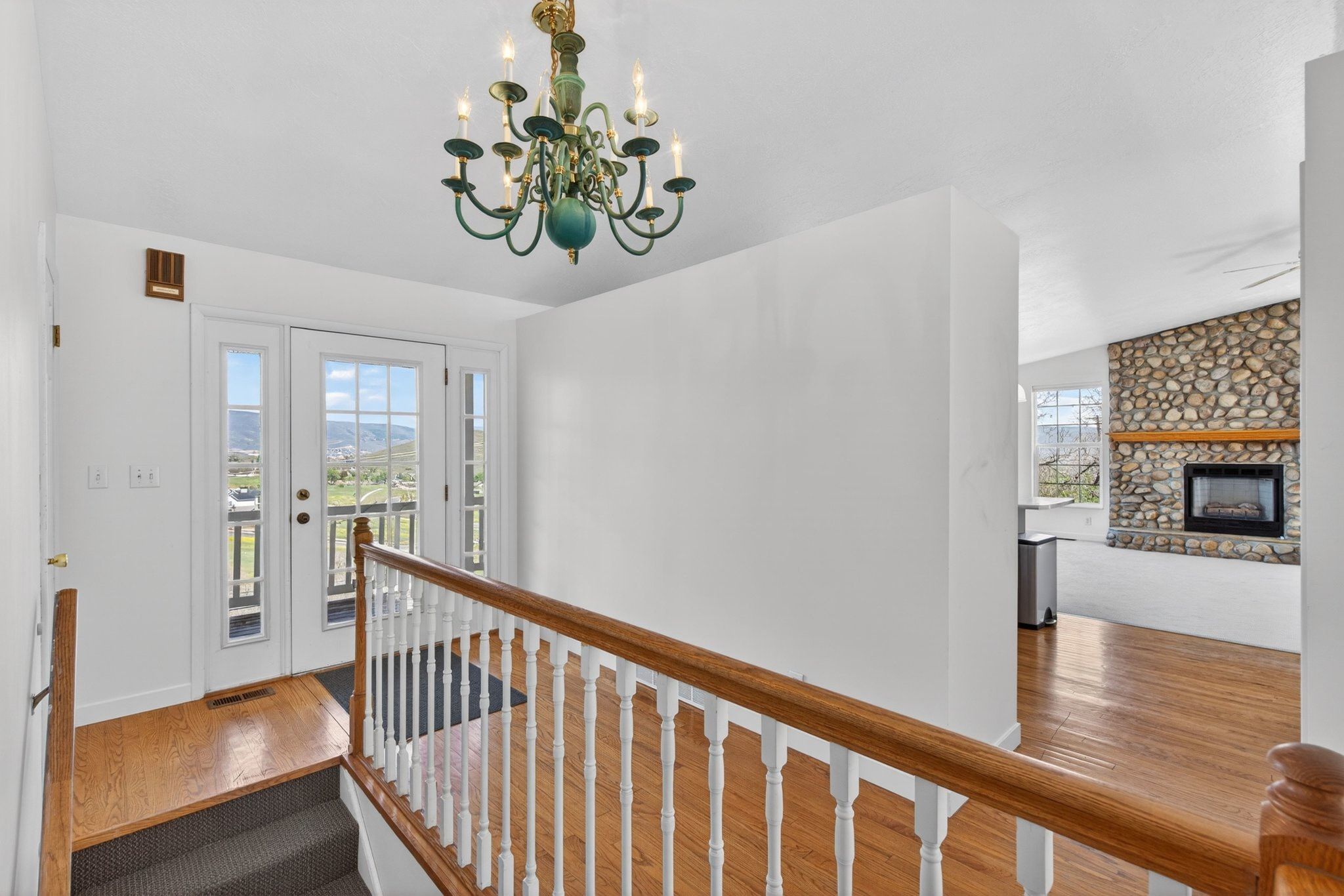 Entryway featuring a decorative chandelier, white French doors with sidelights, and light wood-finish flooring