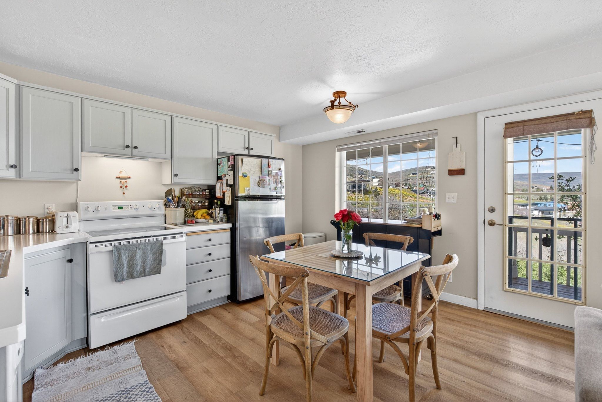 Kitchen dining area featuring wood-finish flooring, light grey cabinetry, and white appliances