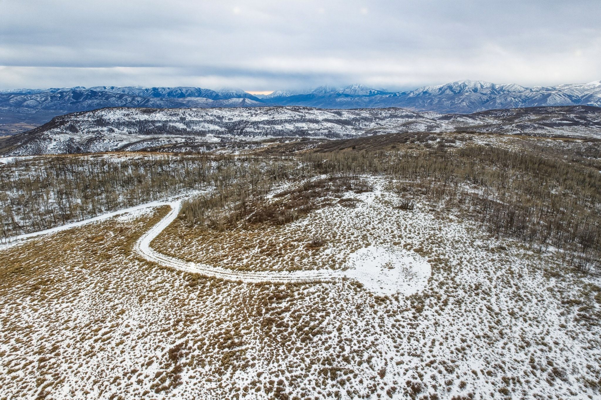 Expansive, snow-dusted landscape featuring a winding access road