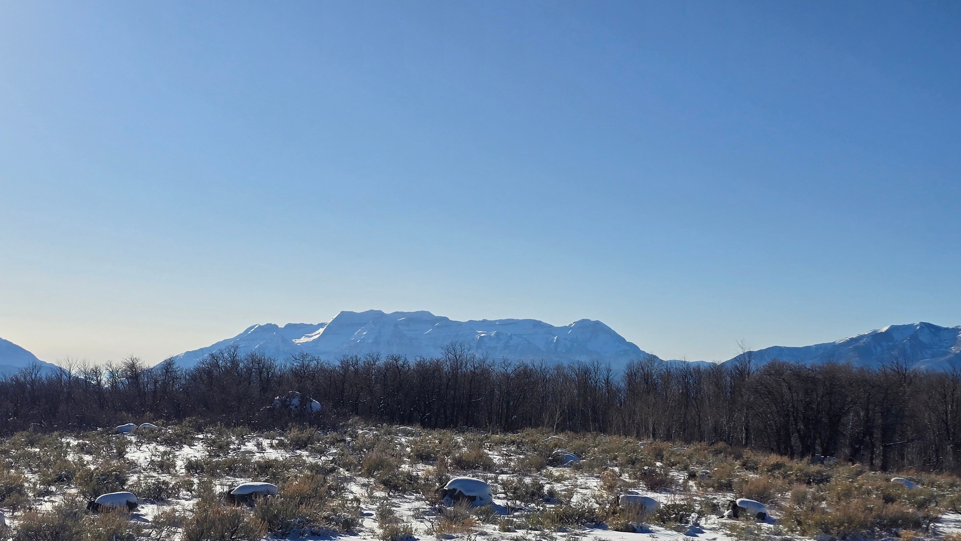Expansive mountain backdrop featuring snow-capped peaks and a clear blue sky