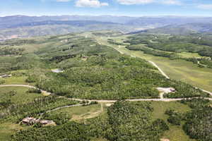 Expansive mountain landscape featuring varied terrain, a winding road, and scattered residential structures