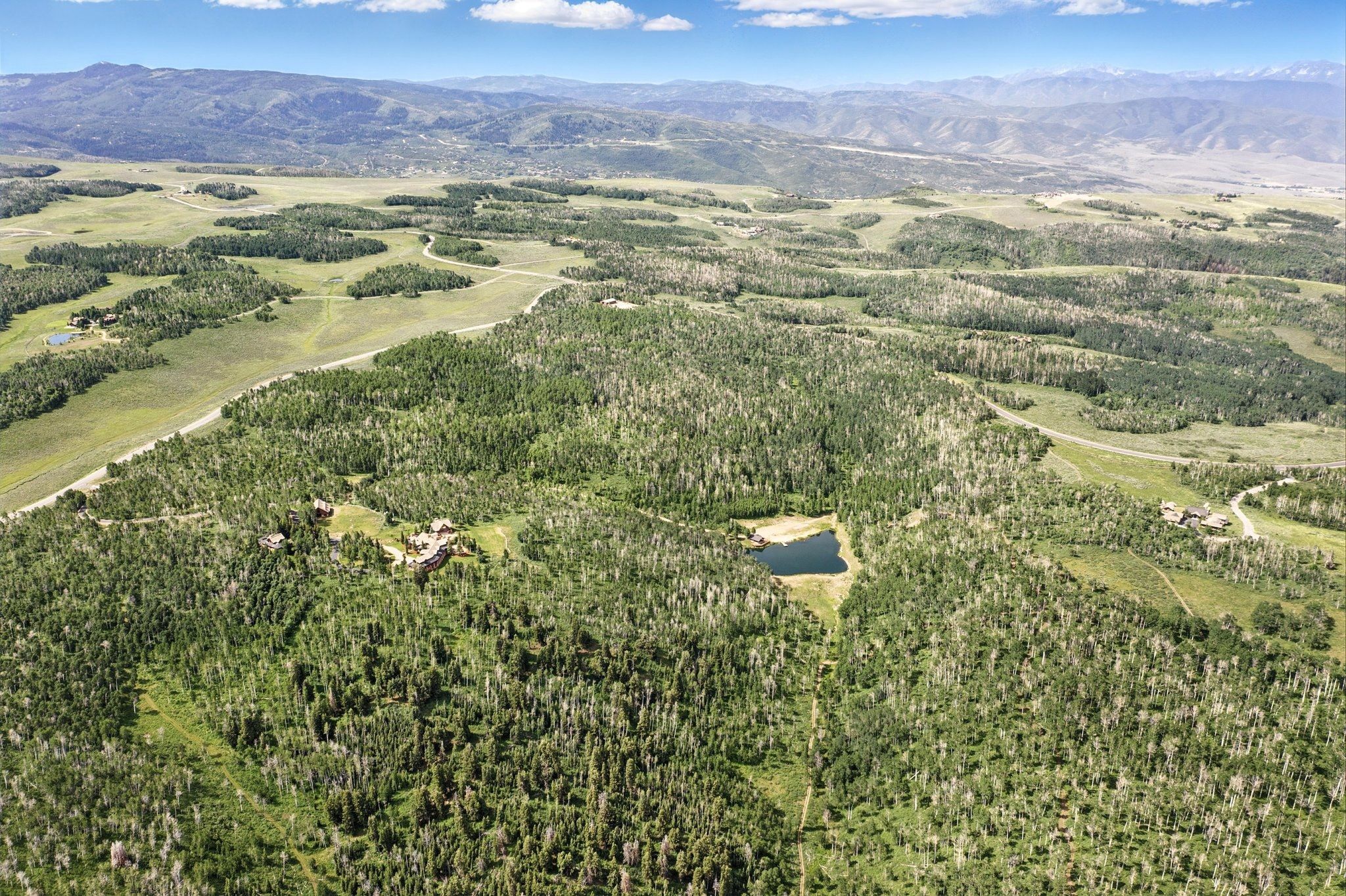 Expansive acreage featuring dense wooded areas, open clearings, and distant mountain ranges