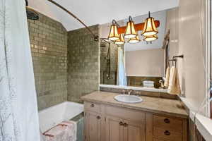 Bathroom featuring a tub/shower combination with subway tile surround, a single vanity with a stone-finish countertop, undermount sink, and wood-finish cabinetry