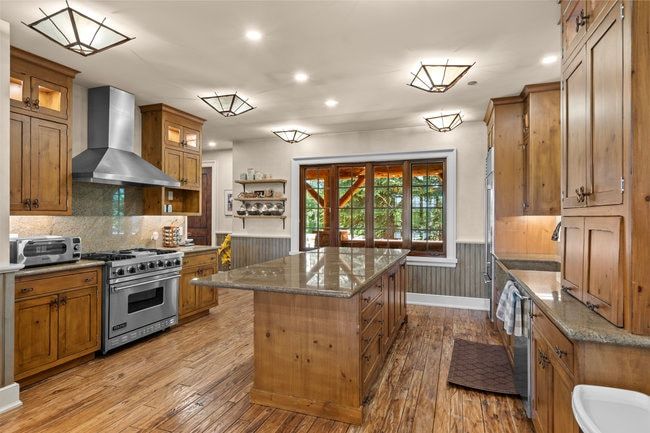 Kitchen featuring wood-finish flooring, custom wood cabinetry, and a central island with a stone countertop
