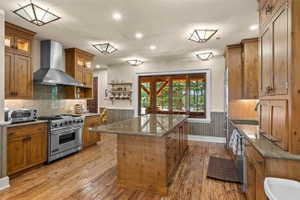 Kitchen featuring wood-finish flooring, custom wood cabinetry, and a central island with a stone countertop