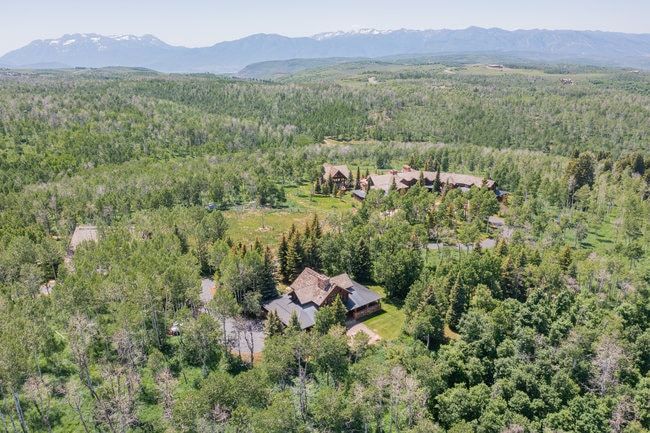 Expansive wooded landscape featuring multiple properties and distant mountains
