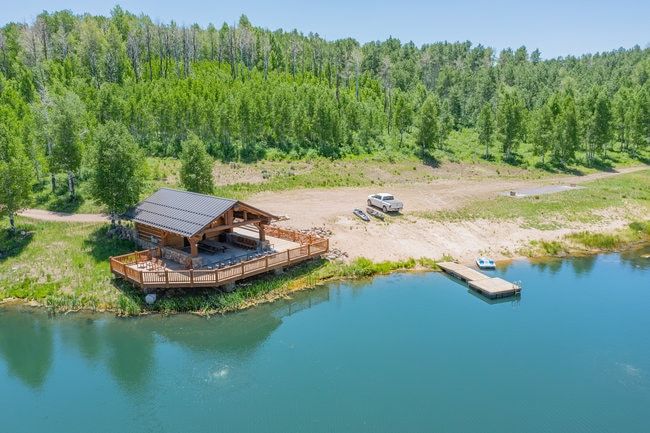 Lakefront property featuring a covered log cabin-style pavilion with a spacious wooden deck and a private dock