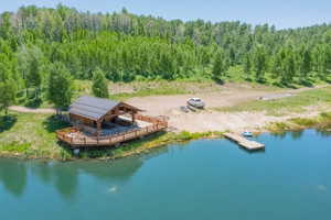 Lakefront property featuring a covered log cabin-style pavilion with a spacious wooden deck and a private dock