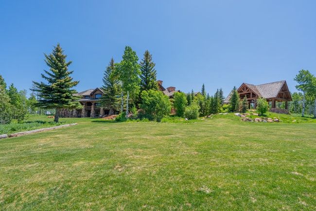 Expansive green lawn bordering a stone and timber-frame residence