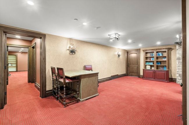 Spacious interior room featuring textured wall coverings, recessed lighting, and a built-in wood cabinet with shelving