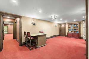 Spacious interior room featuring textured wall coverings, recessed lighting, and a built-in wood cabinet with shelving