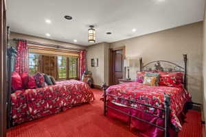 Room featuring a wide window with exterior tree-lined scenery, recessed lighting, a central ceiling light fixture, wood-finish trim, and a paneled door