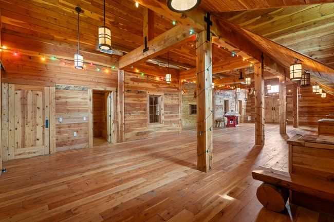 Spacious interior featuring extensive wood-finish flooring, exposed wooden beams, and plank wood walls