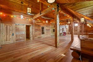 Spacious interior featuring extensive wood-finish flooring, exposed wooden beams, and plank wood walls