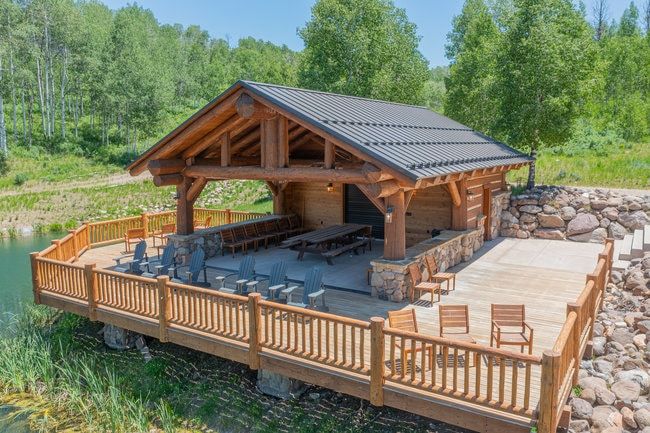 Expansive waterside deck featuring a robust log construction structure with a metal roof