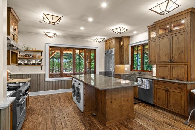 Spacious kitchen featuring wood-finish flooring, custom wood cabinetry, granite countertops, and stainless steel appliances