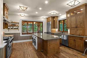 Spacious kitchen featuring wood-finish flooring, custom wood cabinetry, granite countertops, and stainless steel appliances