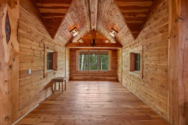Expansive room featuring natural wood plank walls, exposed wood beam ceiling, and wood-finish flooring