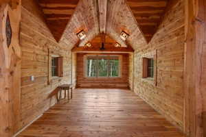 Expansive room featuring natural wood plank walls, exposed wood beam ceiling, and wood-finish flooring