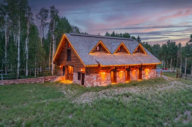 Log cabin style exterior featuring a stone foundation, a gabled roof, and three prominent dormers