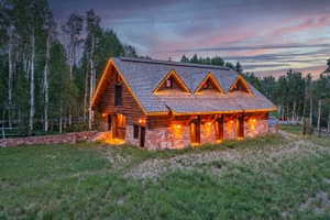 Log cabin style exterior featuring a stone foundation, a gabled roof, and three prominent dormers