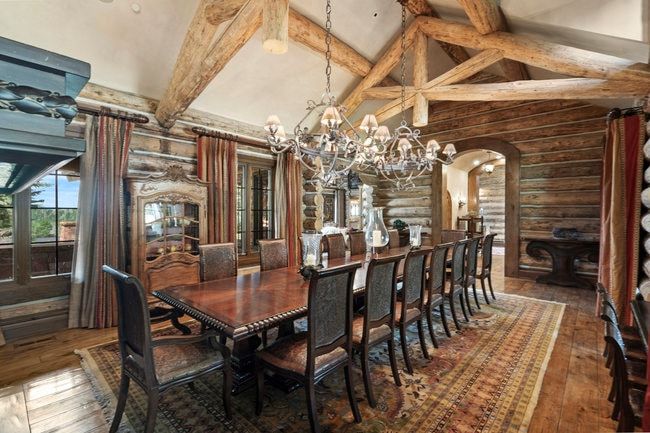 Spacious dining area featuring exposed wood beams, a log wall finish, wood-finish flooring, and multiple windows