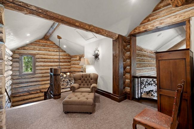 Loft area with vaulted ceilings, exposed log beams, log walls, and a wrought iron balustrade with a tree motif