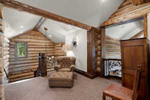 Loft area with vaulted ceilings, exposed log beams, log walls, and a wrought iron balustrade with a tree motif