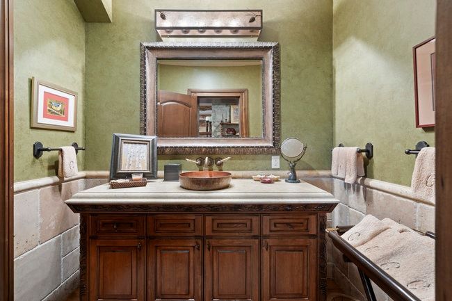Vanity area featuring a stone-look countertop, integrated copper vessel sink, and ornate framed mirror