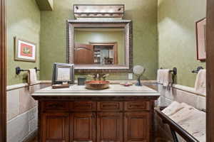 Vanity area featuring a stone-look countertop, integrated copper vessel sink, and ornate framed mirror