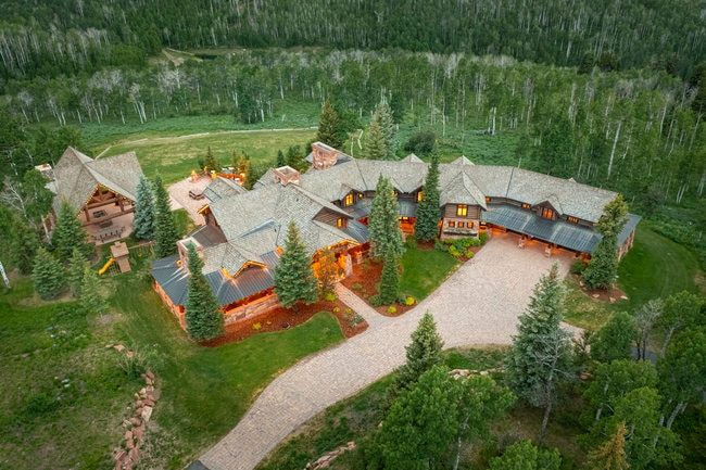 Expansive rustic-style residence featuring a multi-gabled roofline, stone and wood-clad exterior, and a gravel driveway