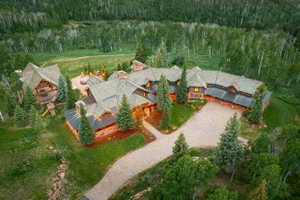 Expansive rustic-style residence featuring a multi-gabled roofline, stone and wood-clad exterior, and a gravel driveway