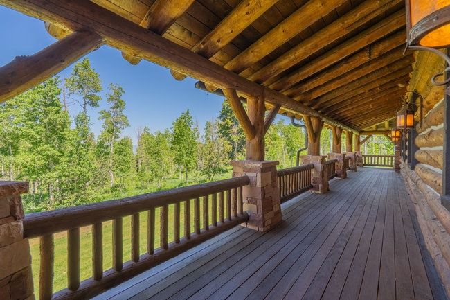 Expansive covered deck featuring natural log and stone architectural elements