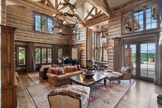 Expansive living area featuring exposed log walls, a vaulted ceiling with exposed wood beams, and wood-finish flooring